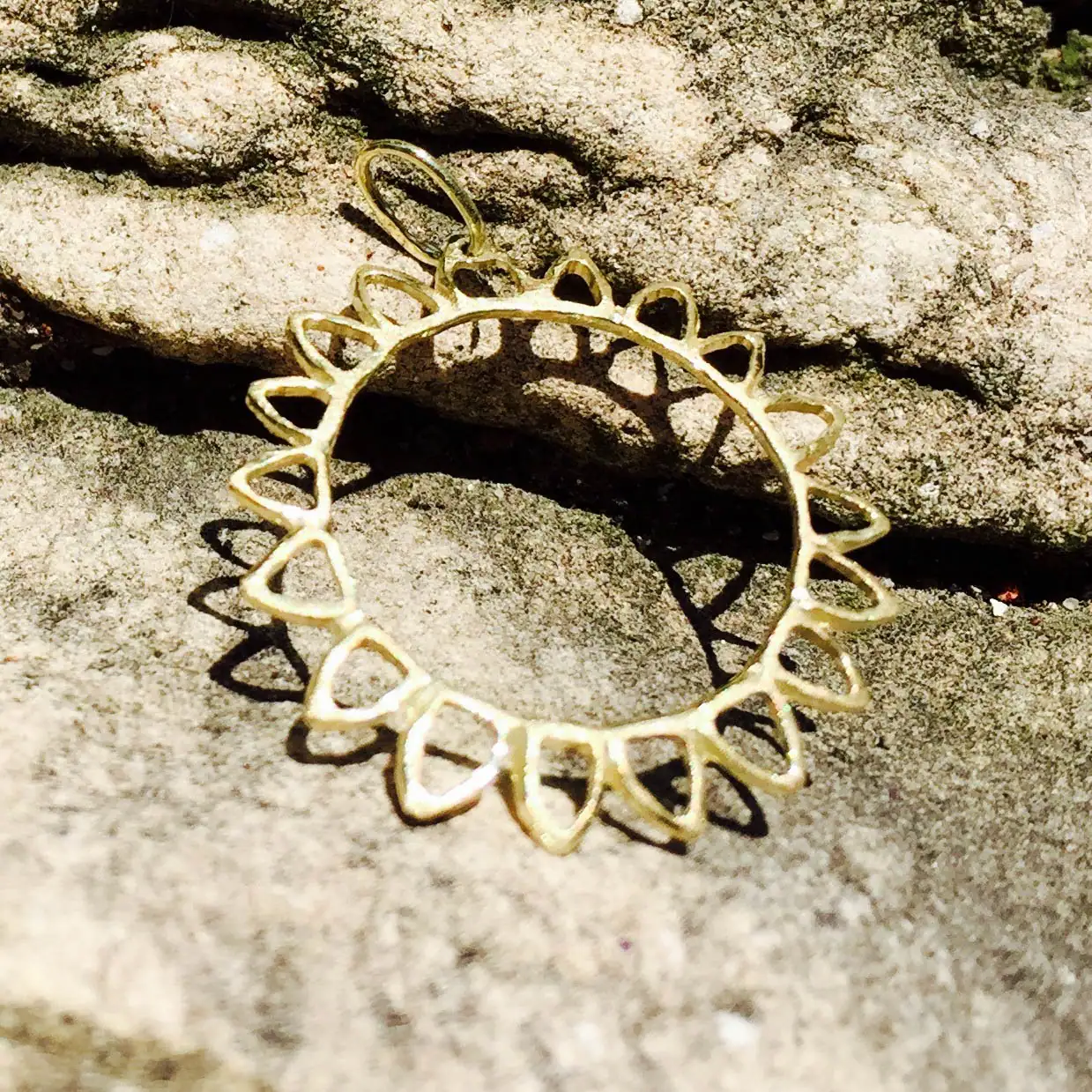 Auf Steinplatte liegender Goldanhänger (UNIKAT) , die Form ist eine Sonne-Sonnenblume